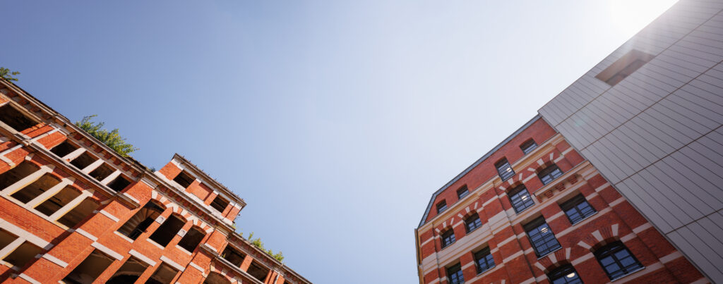 Panorama des Reallabors ZEKIWA Zeitz. Links ein altes Backsteingebäude ohne Fenster, rechts ein sanierter Gebäudeteil