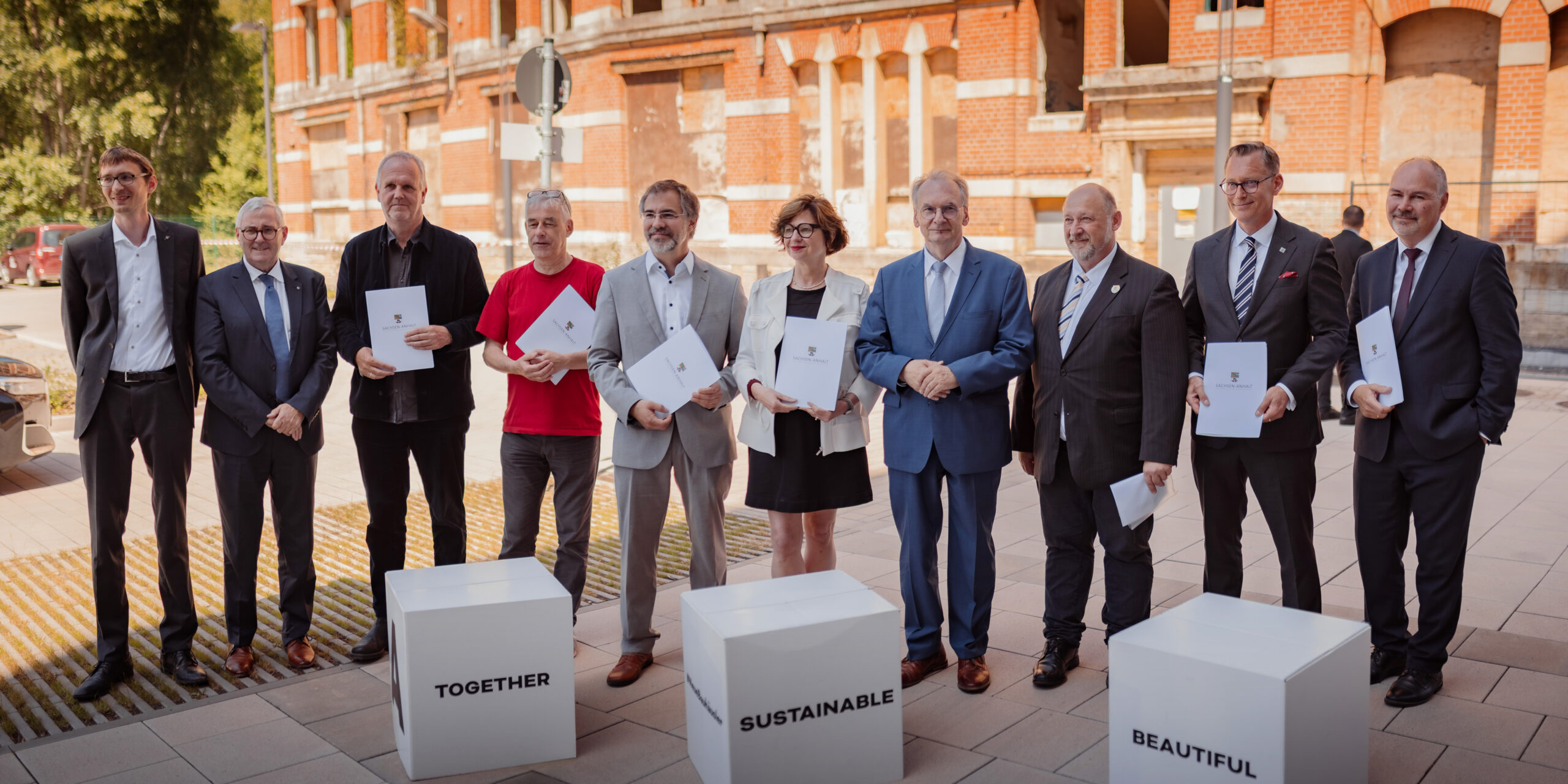 Gruppenfoto der Übergabe mit den Leiter:innen der beteiligten Institutionen und Ministerpräsident Dr. Rainer Haseloff. Davor drei große Würfel mit den Aufschriften: Together, Sustainable und Beautiful